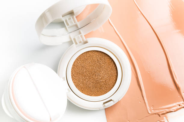 Foundation cushion with sponge and puff on half of the surface of a tonal base, smeared on a white background